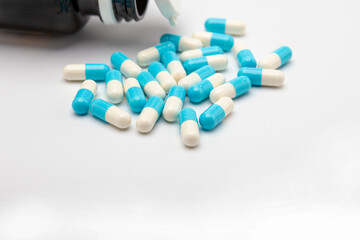 Many capsule pills and drug bottle on white background
