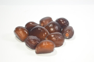 Close-up stack of shiny, dark brown hard seeds from the Salak fruit (Snake Fruit) against a white background. Concept for botanical waste, natural texture, tropical flora, and raw material.
