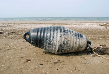 black buoy resting on the sand