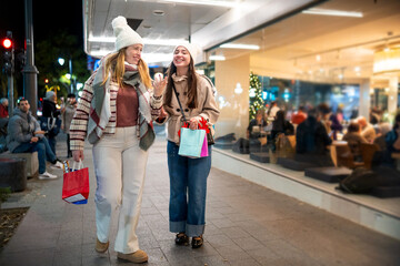 Obraz premium Gen z women enjoying christmas shopping on city street