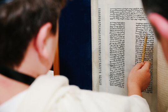 Jewish Person Reading from an Open Torah Scroll Using a Golden Yad (Pointer) During a Bar Mitzvah or Synagogue Service