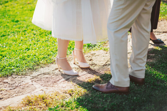 Couple standing on a stone path during a wedding in a garden on a sunny day with guests nearby preparing for the ceremony - Powered by Adobe