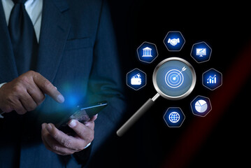 Businessman using smartphone with magnifier glass on target dartboard, Setting financial targets with structured planning. strategy plan concept