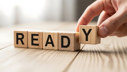 Hand placing final wooden block spelling ready symbolizing preparation for a new business goal or challenge