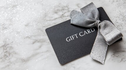 Luxury black gift card decorated with a shiny silver ribbon bow, placed on a white marble surface with scattered glitter, perfect for festive or special occasions.