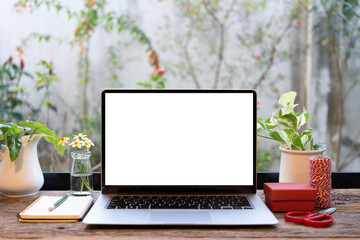 Laptop and red gift box and scissors on wooden table in front of window