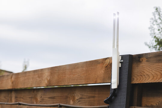 Wi-Fi router outdoor on fence near the house.  Close up photo. - Powered by Adobe