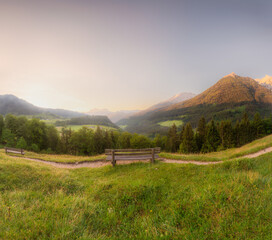 Fototapeta premium Meadow with road and bench during sunset in Berchtesgaden National Park