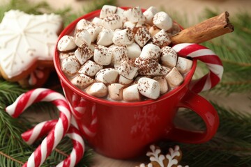 Tasty cocoa with marshmallows, candy canes, gingerbread cookies and Christmas decor on table,...