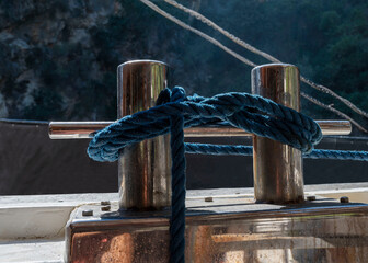 A close-up of a mooring knot attaching a blue rope to a cleat on a boat. Marine rope, marine knot.