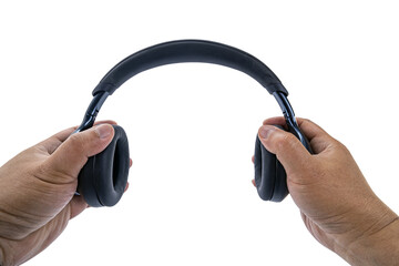 A pair of adult hands are holding black over-ear wireless headphones on a white background with a POV view, as if preparing