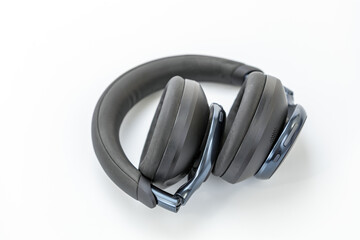 Black wireless over-ear headphones folded with cushioned ear pads and headband, control buttons visible on the ear cup