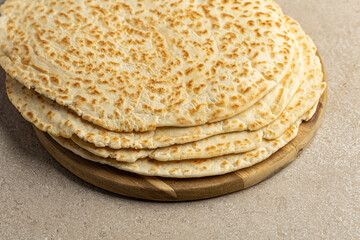 Piadina Romagnola on a wooden serving board. Stack of Italian flatbread, close up.