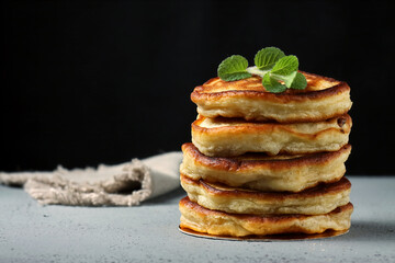 Pancakes with raisins and mint leaf on top.Grey background