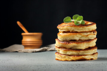 Stack of homemade pancakes with mint on a black background