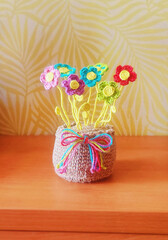 A crochet basket made from colorful jute with flowers