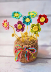 A crochet basket made from colorful jute with flowers