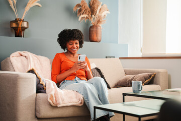 A joyful woman is engaged with her smartphone, smiling as she interacts with her mobile device...