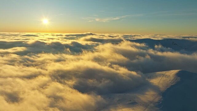 Sunrise bathes snowcapped summits in gold, Vast cloud layer cloaks mountain peaks at early dawn, Serene sunrise illuminates rugged snow mountains veiled by billowing fog