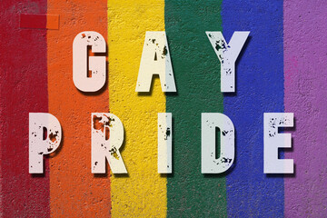 Gay pride. Words written on a wall painted with the colors of the rainbow flag.