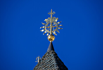 Spire of a side tower of Basilica of the Nativity of Mary with spire and cross before blue sky in the important pilgrimage site of Mariazell in Styria, Austria