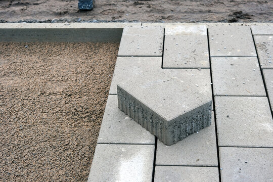 Nahaufnahme von oben auf Pflasterarbeiten f&uuml;r einen Rad- und Gehweg oder einer Einfahrt, ein Pflasterstein im Vordergrund, selektive Sch&auml;rfe, viel Copy Space