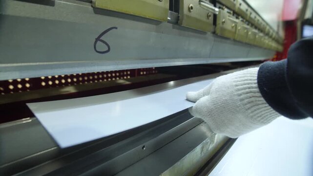 Industrial press brake machine bending metal sheet in metalworking factory.