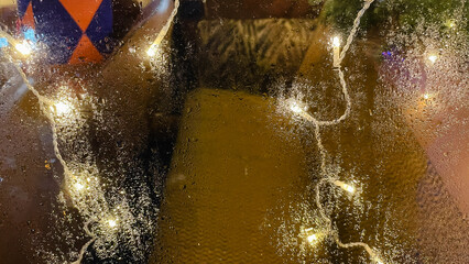 Abstract background of warm bokeh lights and vibrant colors seen through a rain covered window pane