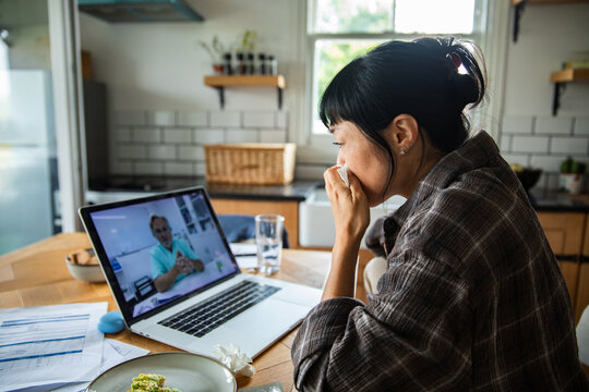 Adult woman feeling sick and worried on telehealth video call at home