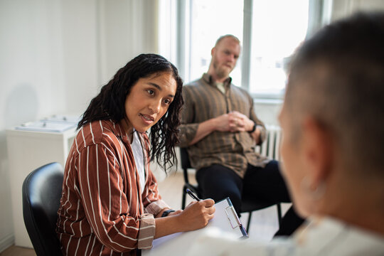 Attentive adult therapist listening in group counseling at clinic