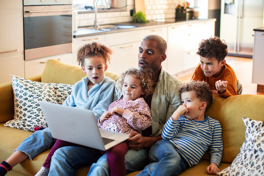 Adult father and children surprised watching laptop on sofa at home