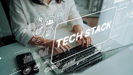 Professional woman researching tech stack concepts and trends on laptop with digital interface and icons in modern workspace. Asymptotic smart data analytic.