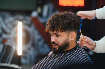 Man getting curly hair fade haircut in barbershop