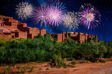Kasbah Ait Ben Haddou with fireworks on the black sky at night in the desert near Atlas Mountains, Morocco
