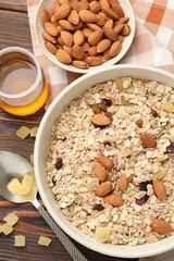 Making granola. Oat flakes, dried fruits, almond nuts and honey on wooden table, flat lay