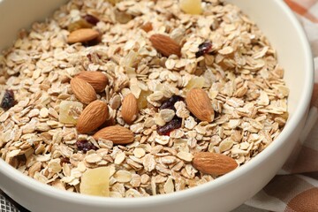 Making granola. Oat flakes, dried fruits and almond nuts in bowl on table, closeup