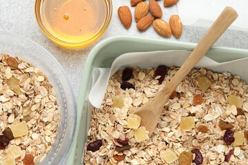 Making granola. Flat lay composition with oat flakes, dried fruits, almond nuts and honey on grey textured table
