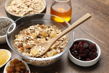 Making granola. Oat flakes with dried fruits in bowl on wooden table, closeup