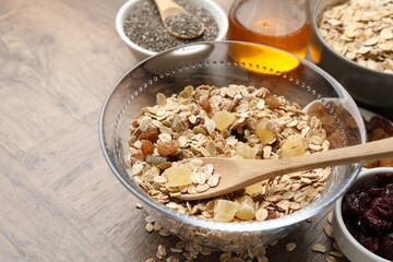 Making granola. Oat flakes with dried fruits in bowl on wooden table, closeup. Space for text