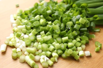 Cut fresh green onions on wooden table, closeup
