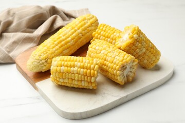 Pieces of boiled corncobs on white marble table, closeup