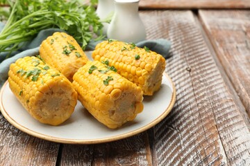 Pieces of boiled corncobs with parsley on wooden table, closeup. Space for text