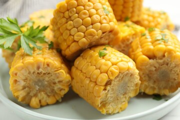 Pieces of tasty corn cobs with parsley on white table, closeup