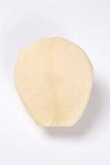 A studio close-up, high-angle shot shows a thick slice of white flesh from a black radish cross-section on a clean white surface