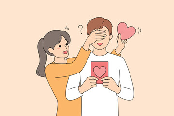 Woman surprising partner with heart card, playful reveal
