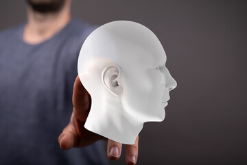 Image of a person holding a white 3D-printed head, representing AI, technology, or the human mind.