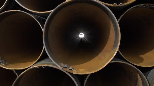 Entering in rusty metal pipe in stack on construction site outdoors.