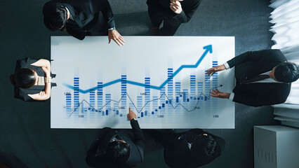 Diverse business team engaged in analyzing financial growth graph on table, showcasing strategy and collaboration in a modern office environment. Scalp