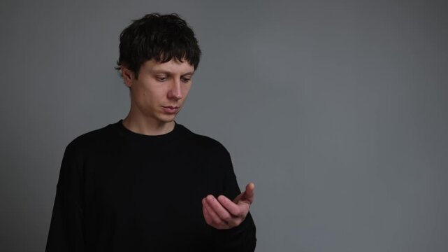 Phantom phone habit digital addiction. Man instinctively reaches for phone not in hand portrait on neutral background