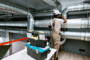 HVAC technician installing ductwork in a modern commercial space during daylight hours